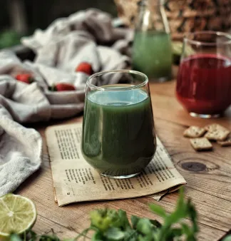 A glass of green juice sitting on top of a newspaper