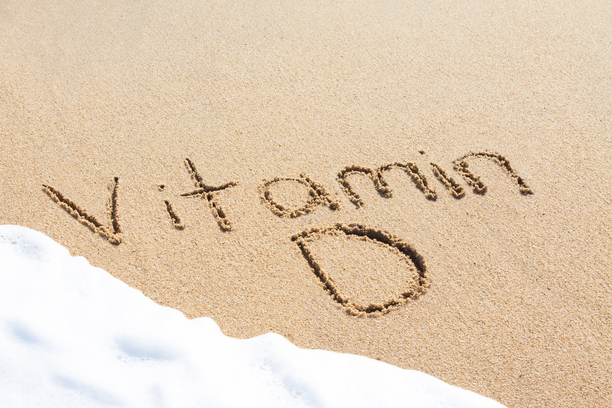 multivitamin with vitamin d writing on sand